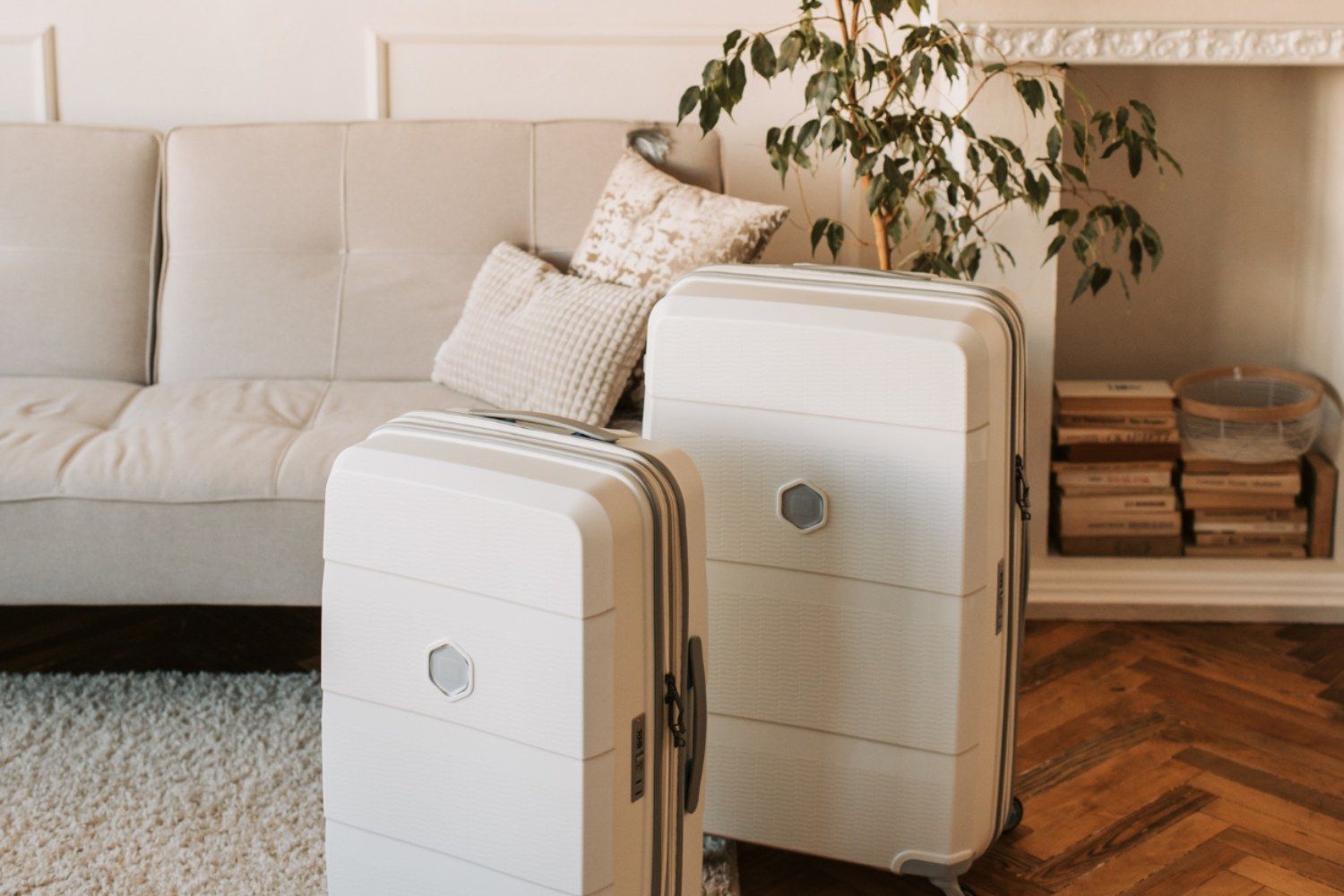Two white suitcases are sitting in a living room next to a couch.