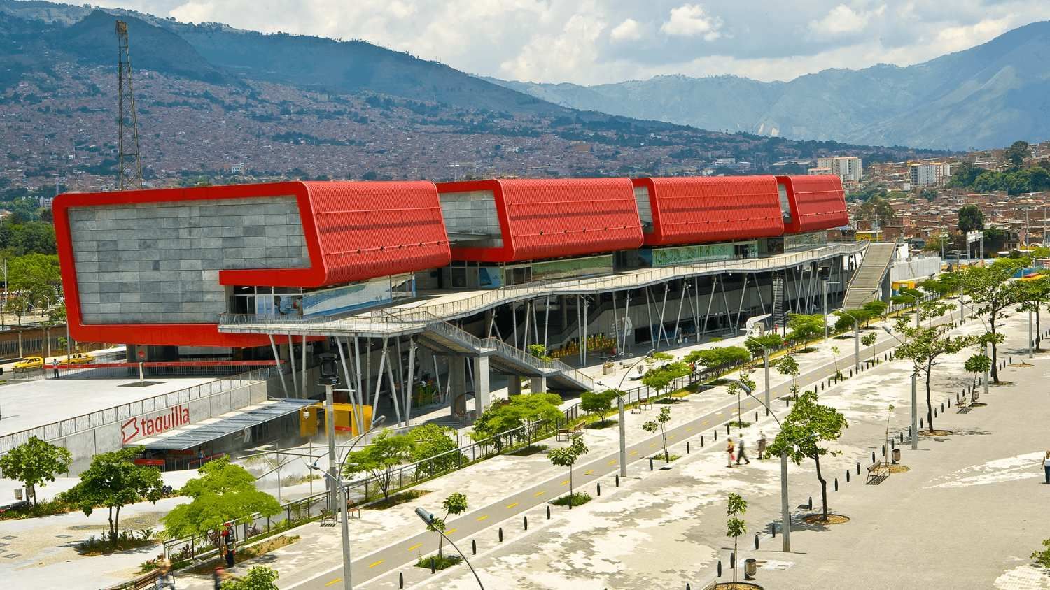 An aerial view of a large red building with mountains in the background.