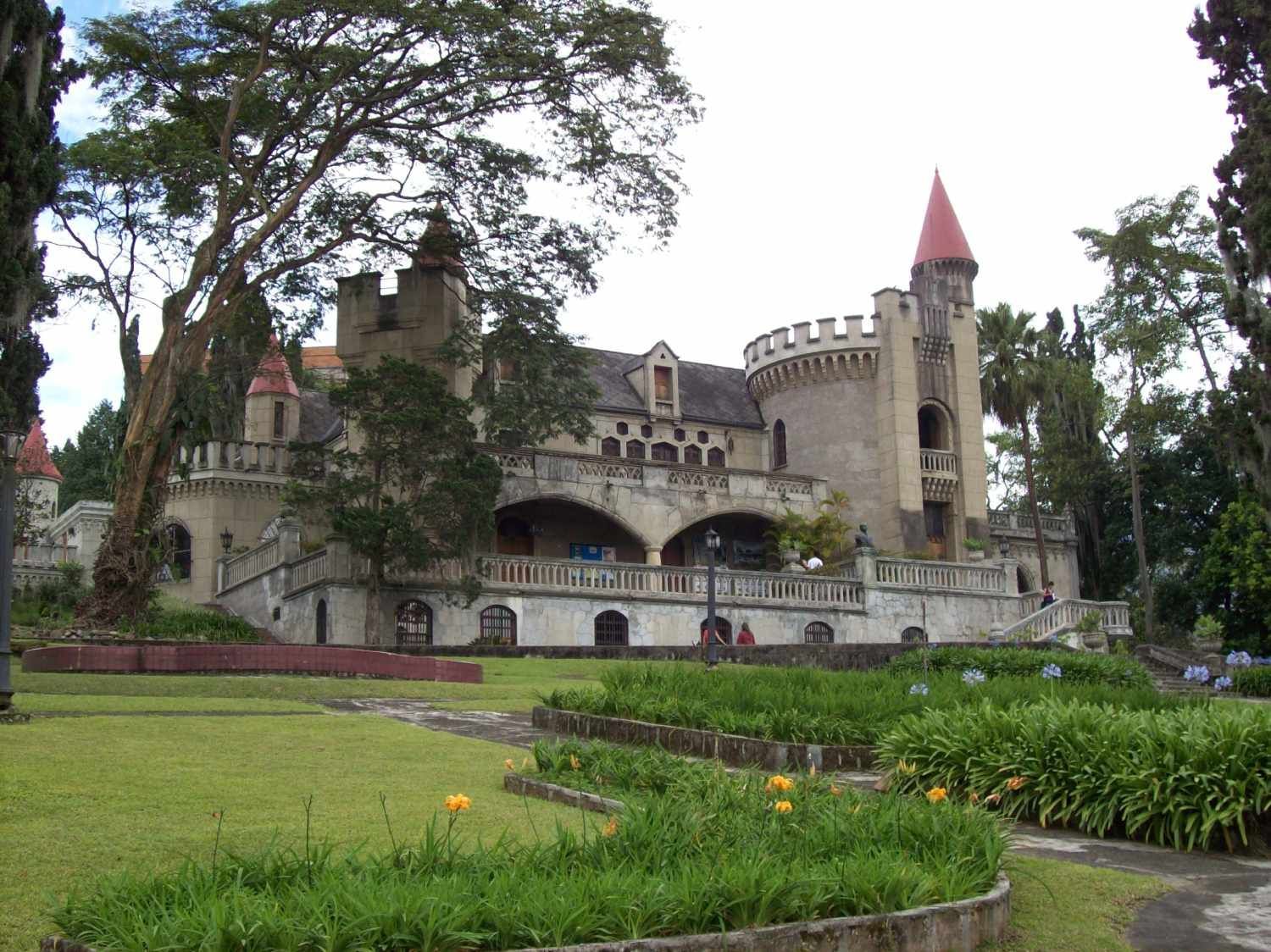 A large castle with a red tower sits in the middle of a park