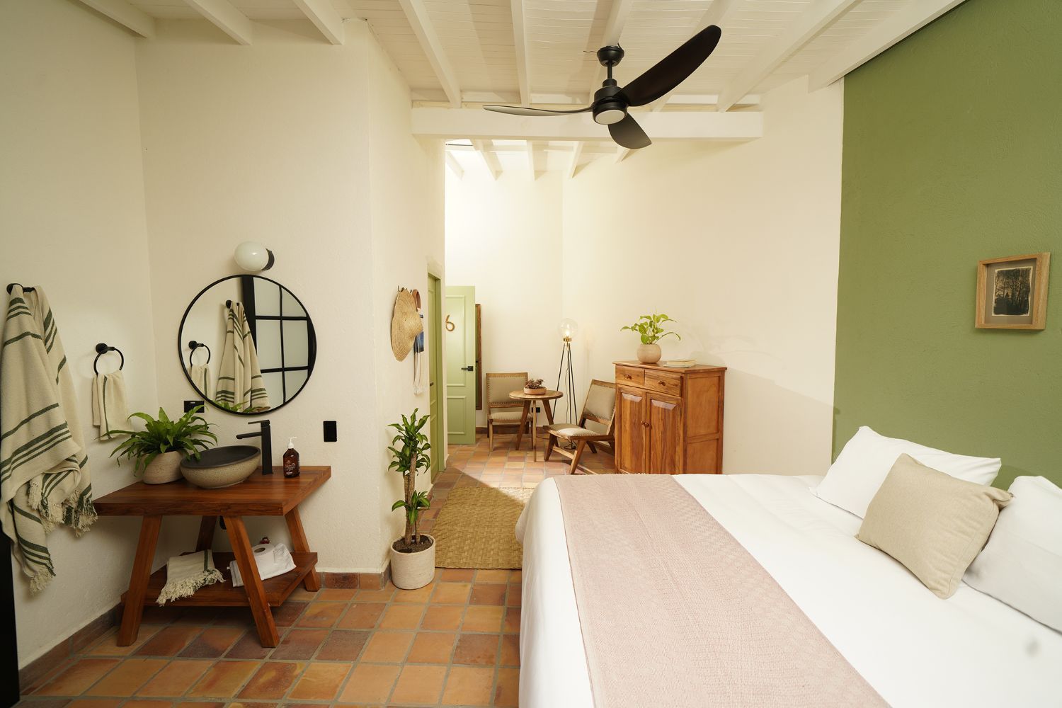A bedroom with a bed , sink , mirror and ceiling fan.