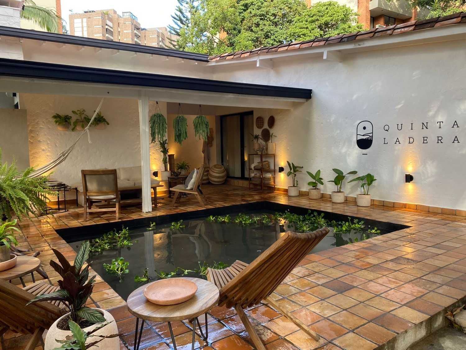 A patio with a pond and chairs in front of a house.