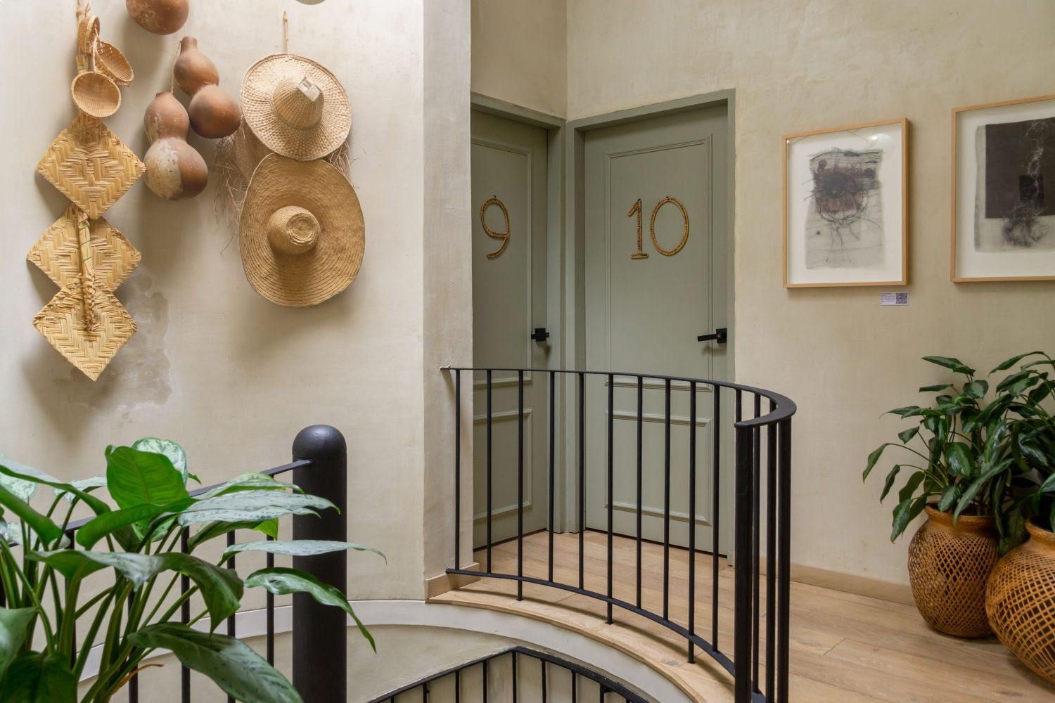 A staircase with a railing leading to a room with a straw hat hanging on the wall.