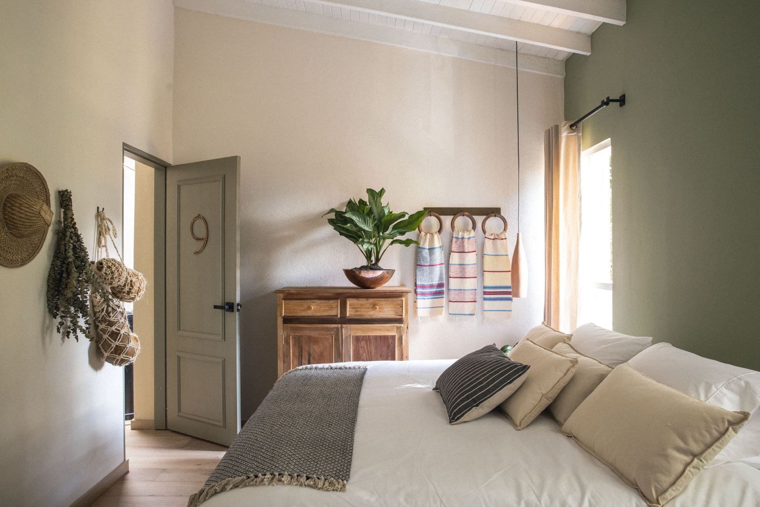 A bedroom with a bed , dresser , and window.