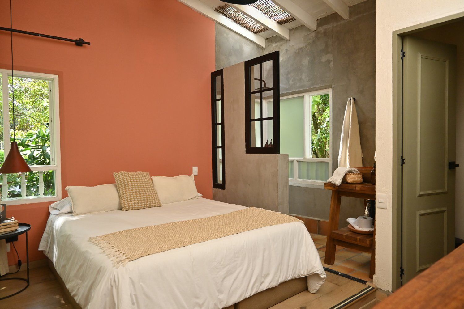 A bedroom with a bed , two windows and a wooden table.