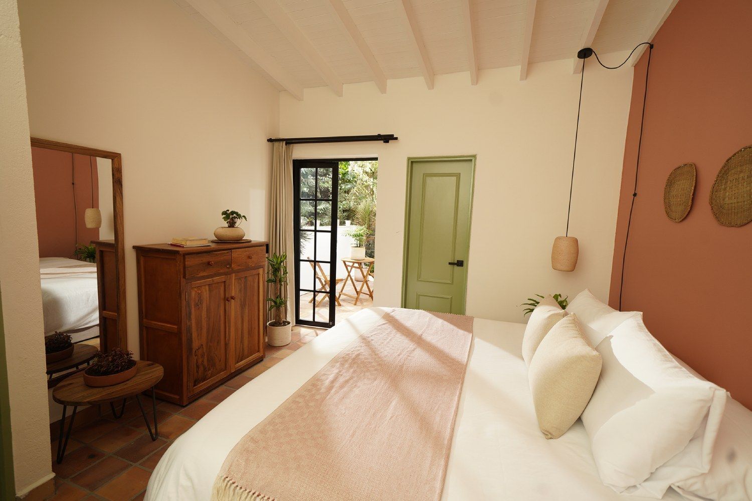 A bedroom with a bed , dresser , mirror and door.