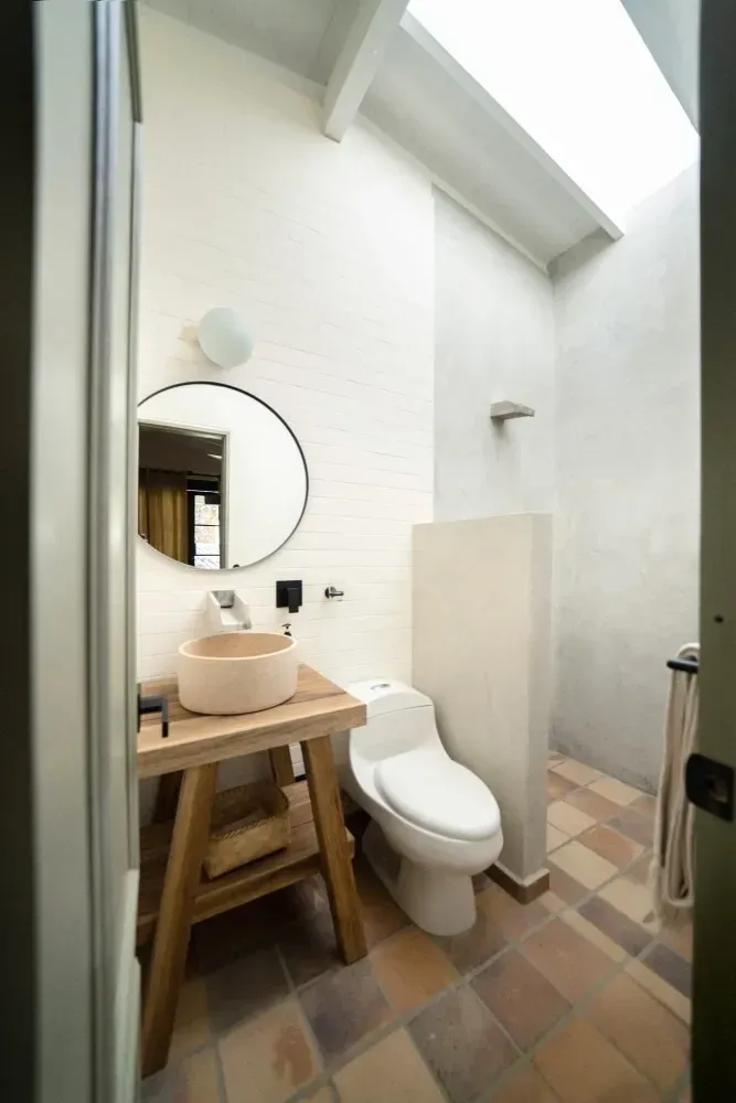 A bathroom with a toilet , sink and mirror.