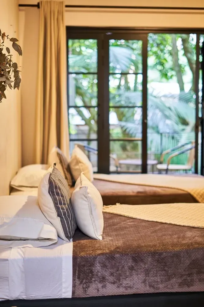 A bedroom with two beds and a sliding glass door.