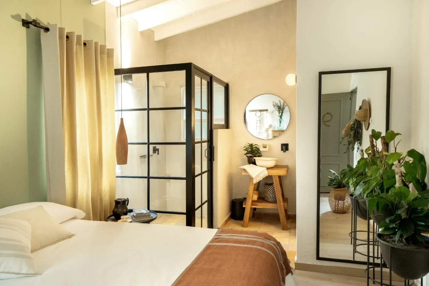 A bedroom with a bed , mirror , sink and shower.