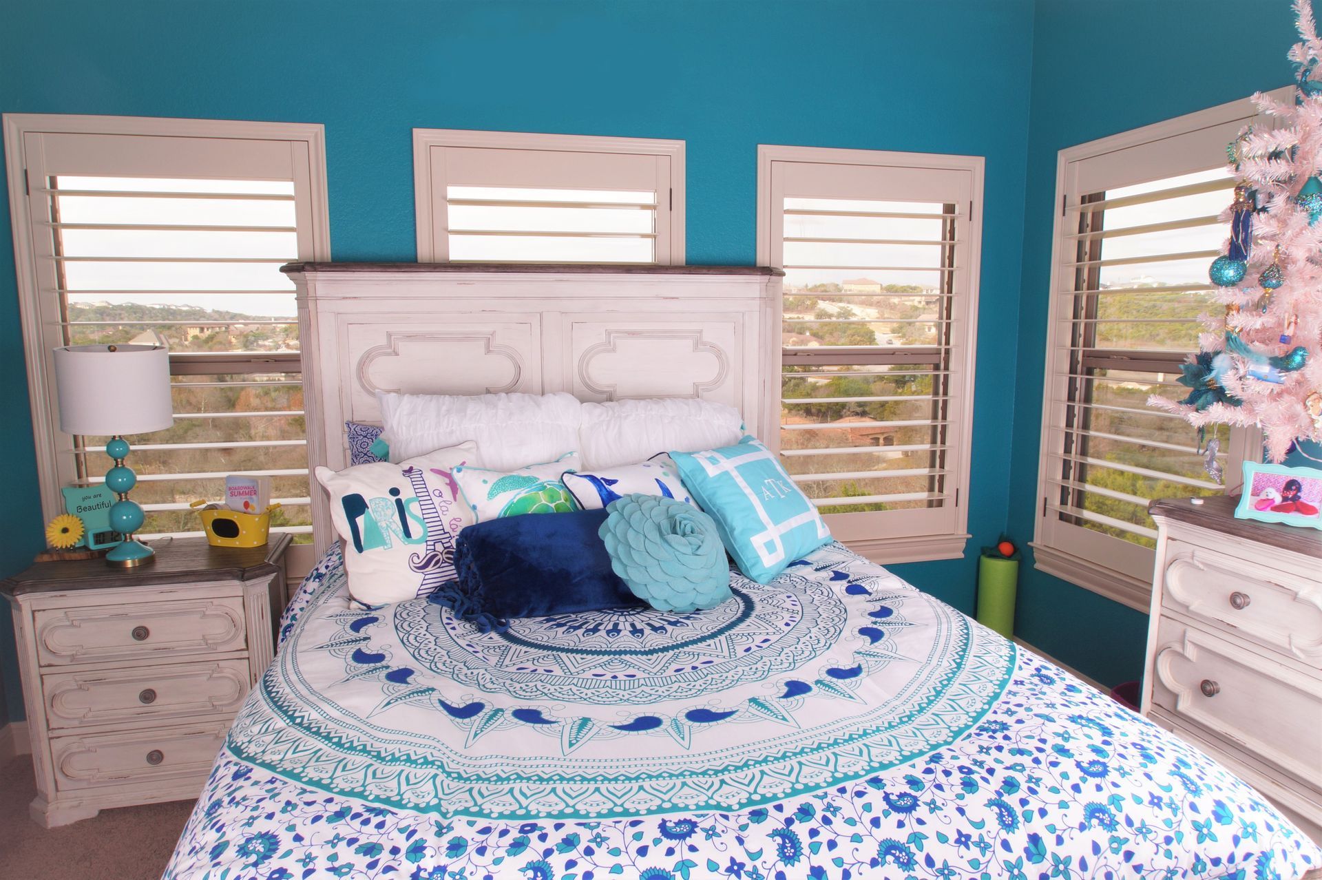White plantation blinds cover the windows in a cheerful, blue child's bedroom in Leander