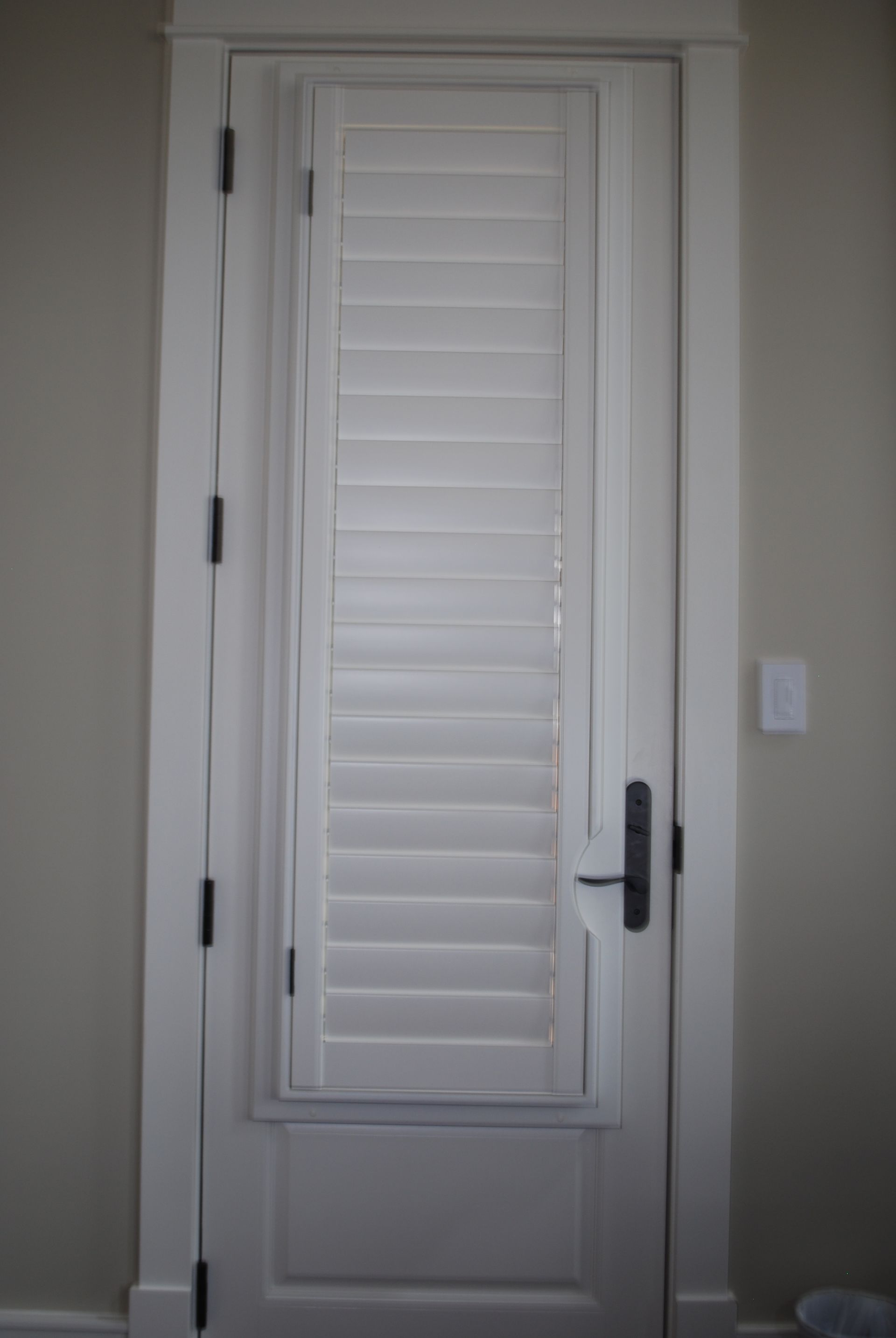 Interior door covered with white plantation shutters