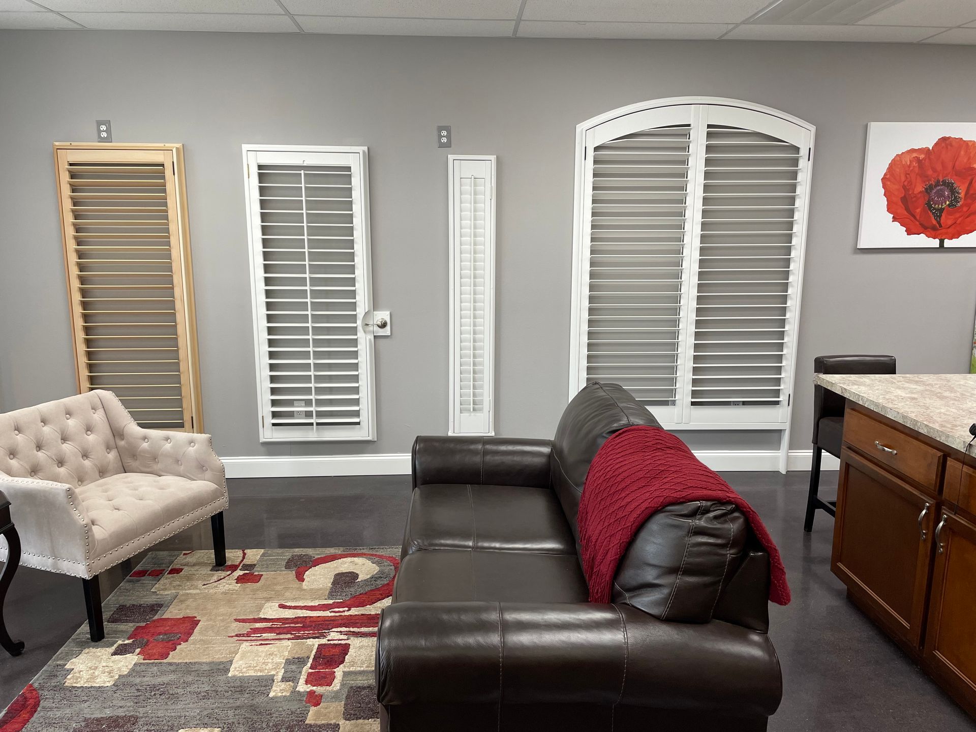 A living room with a couch , chair , rug and shutters on the wall.