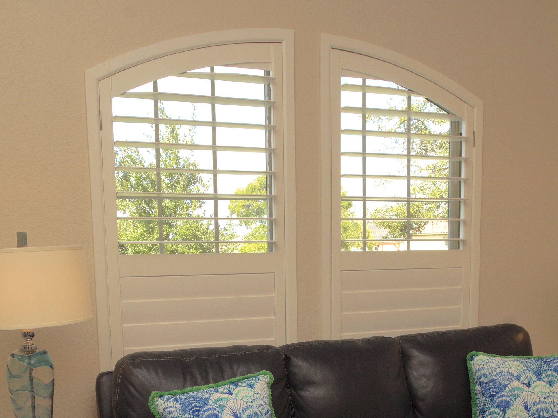 Eyebrow arched living room windows with wood shutters in Austin home