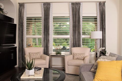 Open cream plantation shutters, with curtains on either side, in elegant sitting area in Austin home

