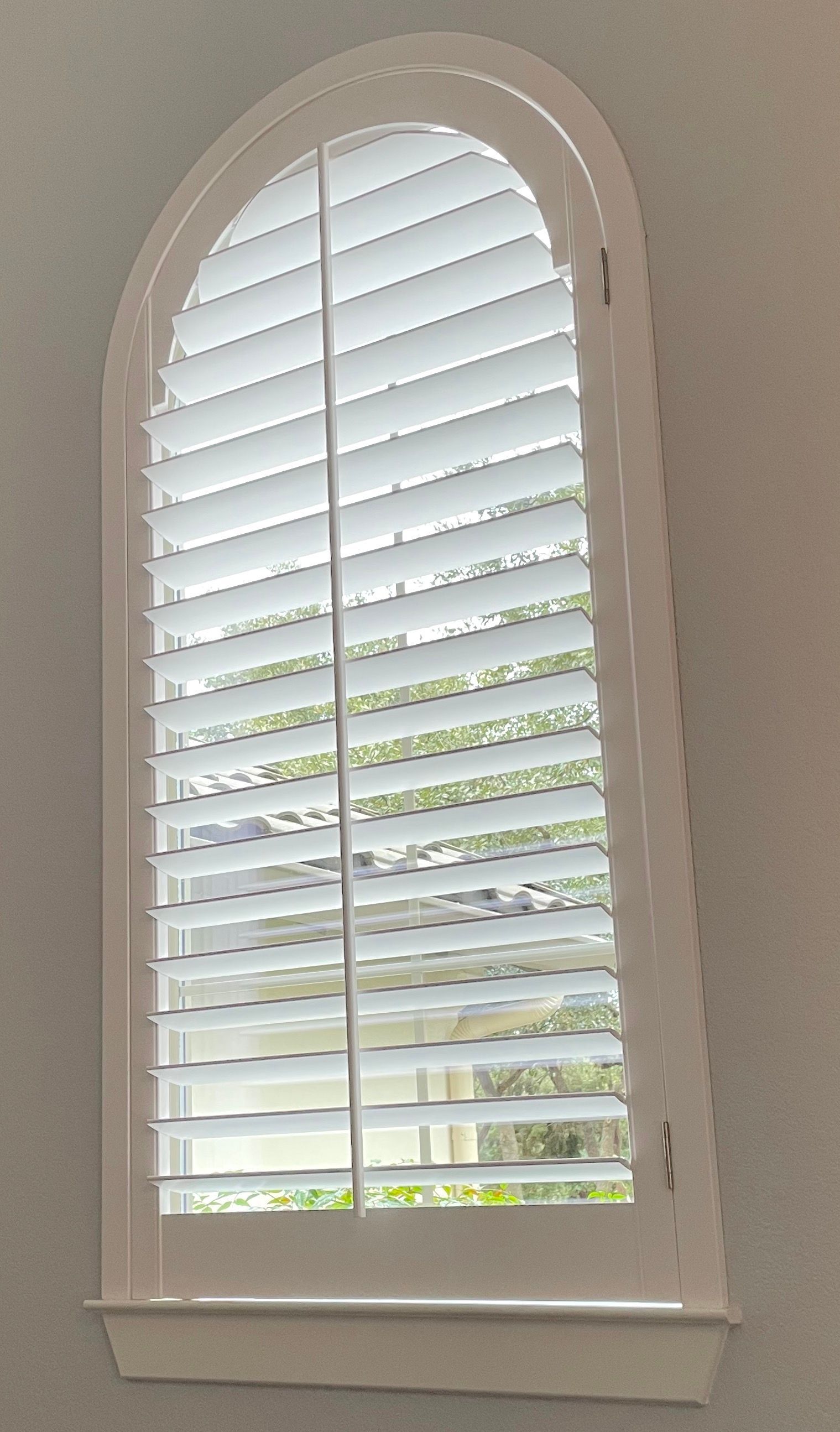 A white arched window with white shutters on it