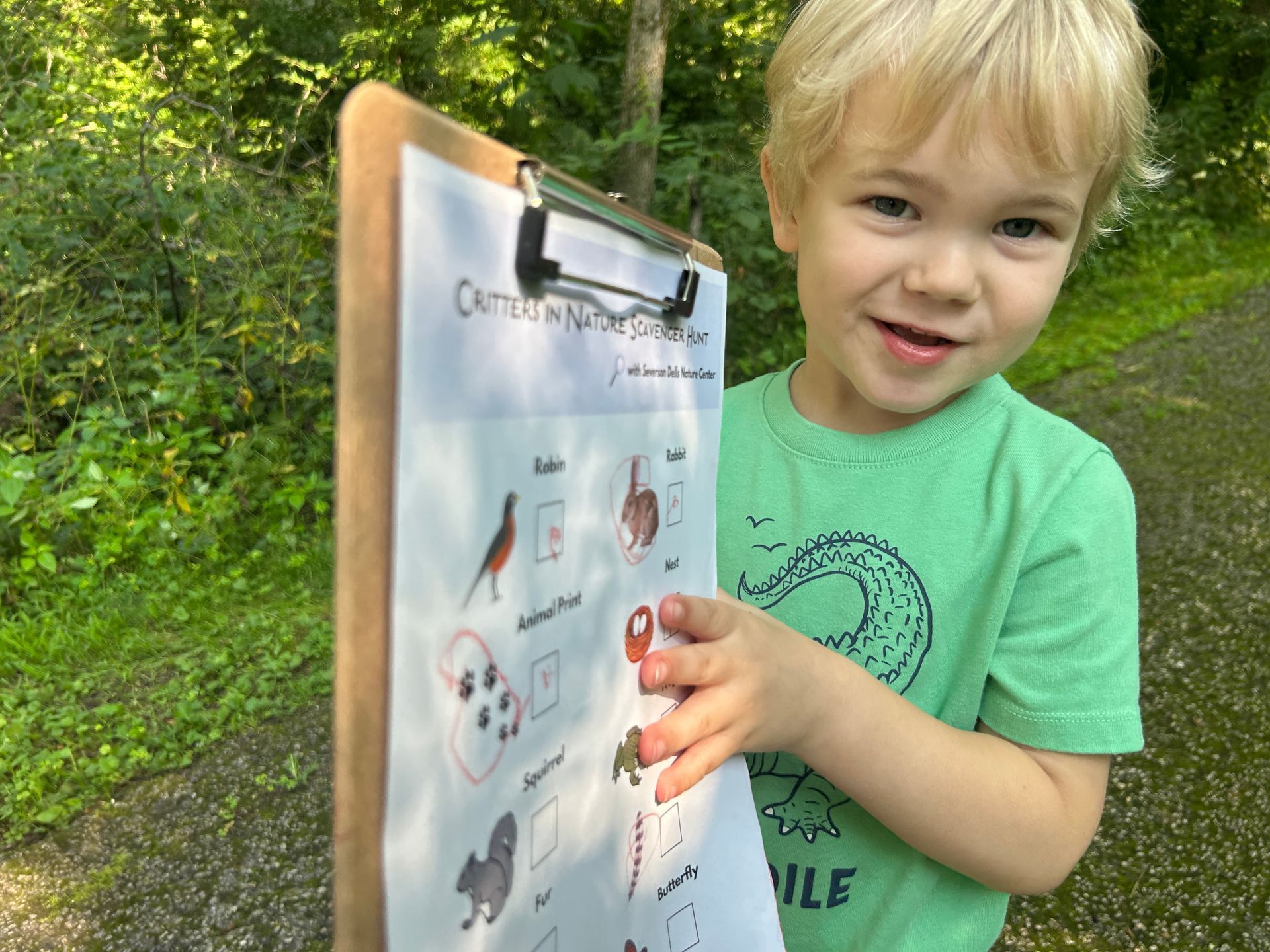 Child holding clipboard with the Critters in Nature Scavenger hunt activity.