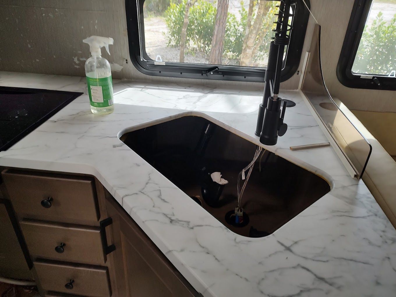 A kitchen sink with a spray bottle on the counter.