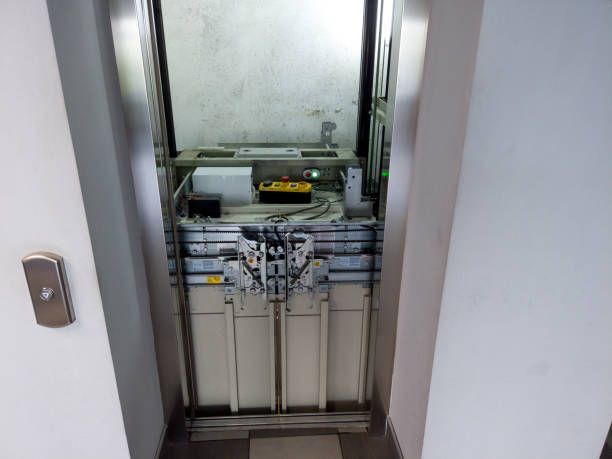 The inside of an elevator with the door open and a button on the wall.