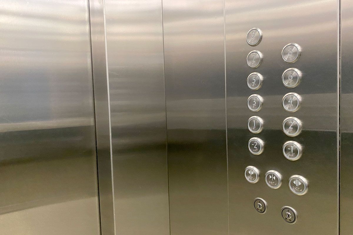 A close up of a stainless steel elevator with buttons on the wall.