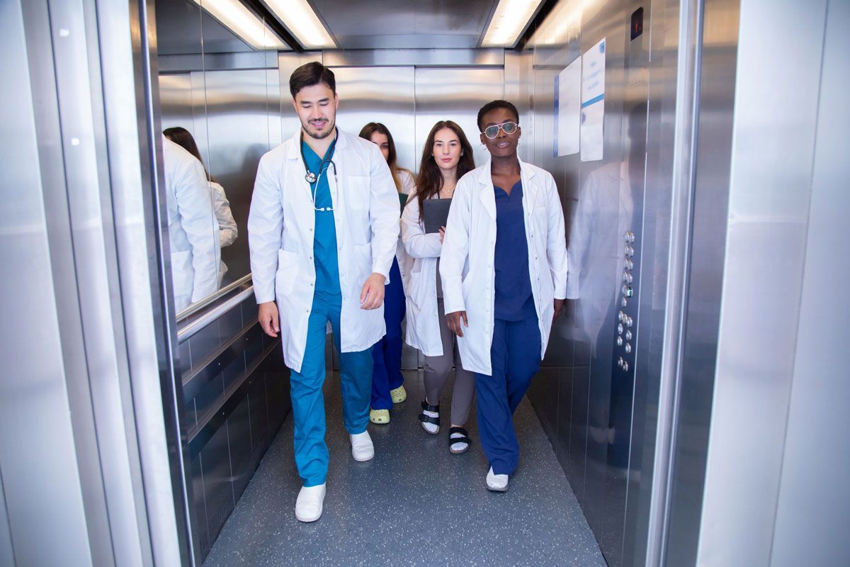 A group of doctors and nurses are walking down an elevator.