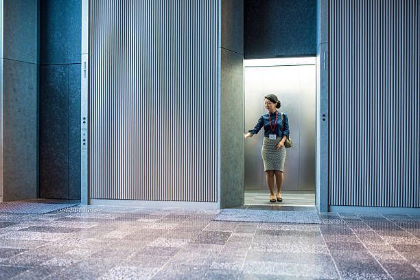 A woman is standing in an elevator in a building.
