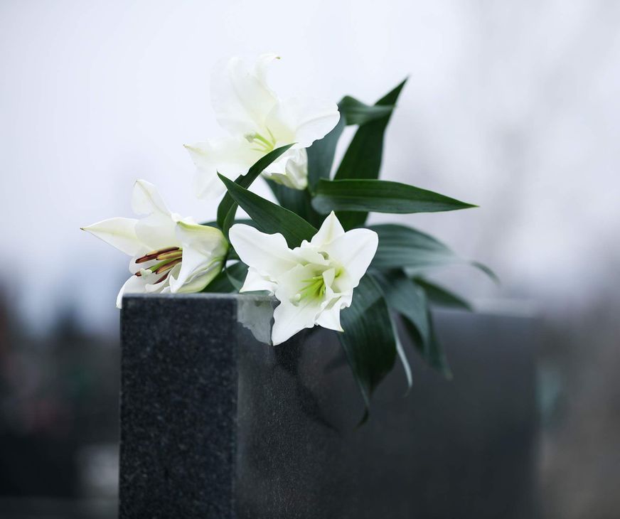 A gravestone with white flowers and green leaves on it