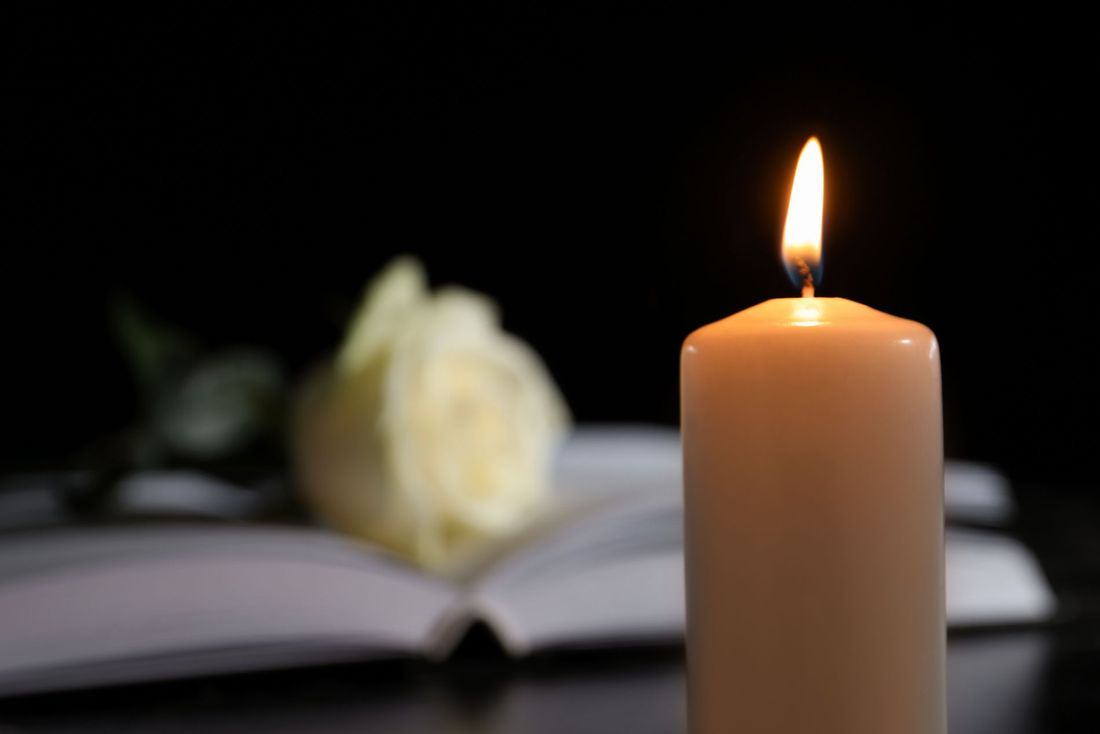 Un cero funebre acceso di fronte a un libro e a una rosa bianca
