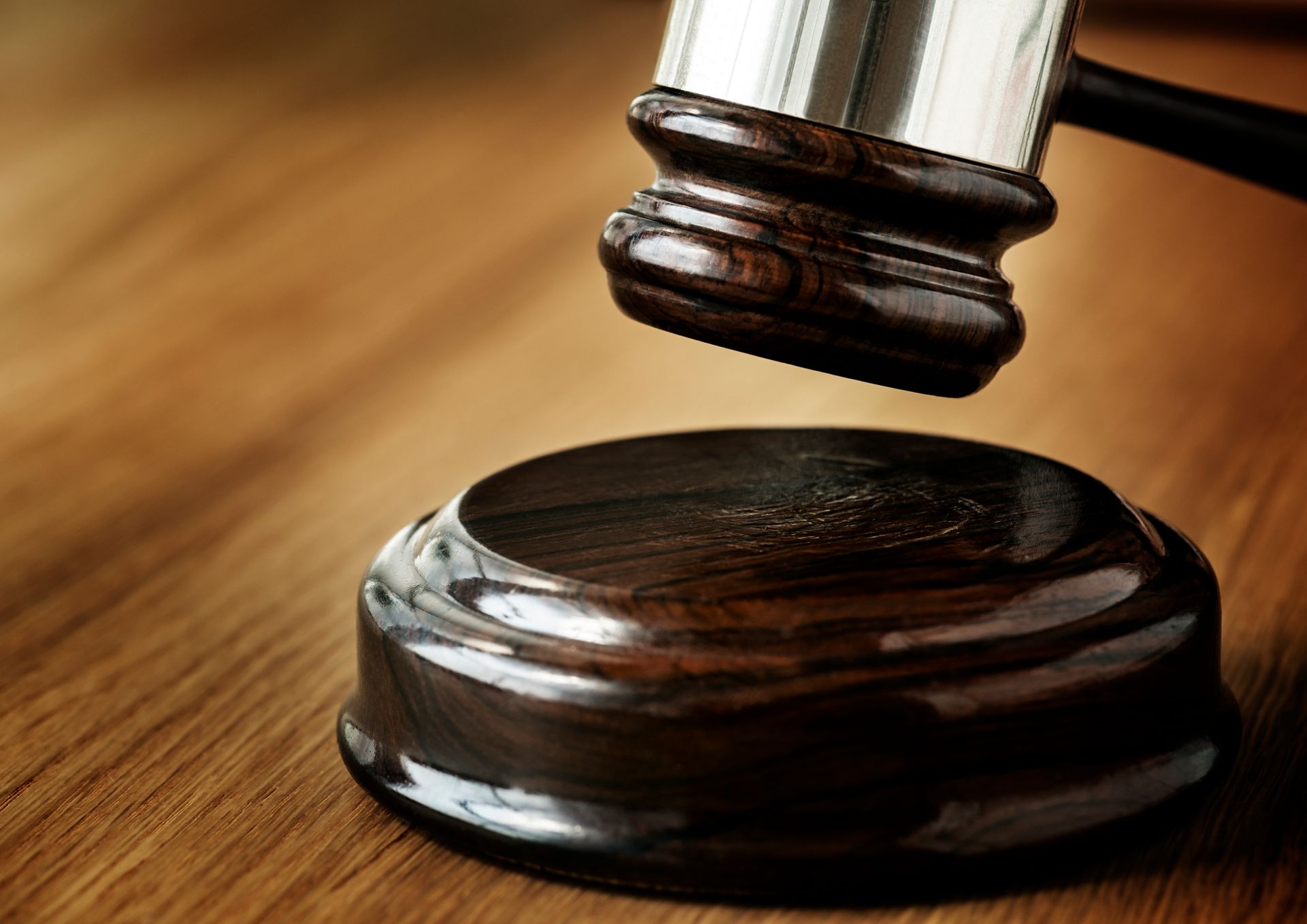 A wooden judge 's gavel is sitting on a wooden table.