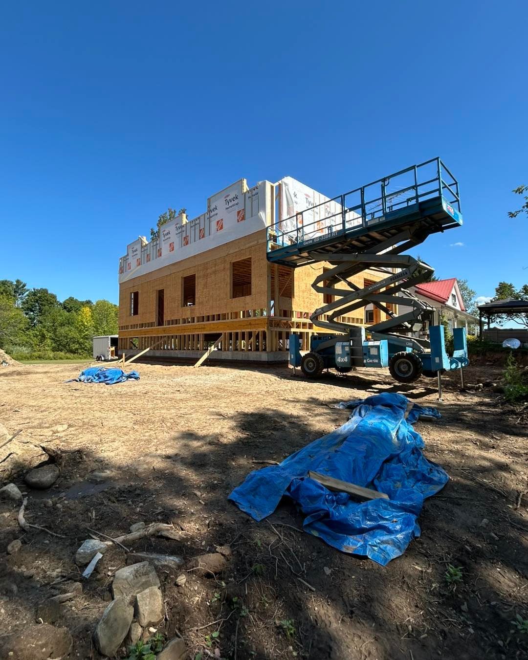 Bâtiment en construction avec un ascenseur bleu devant. Journée ensoleillée.