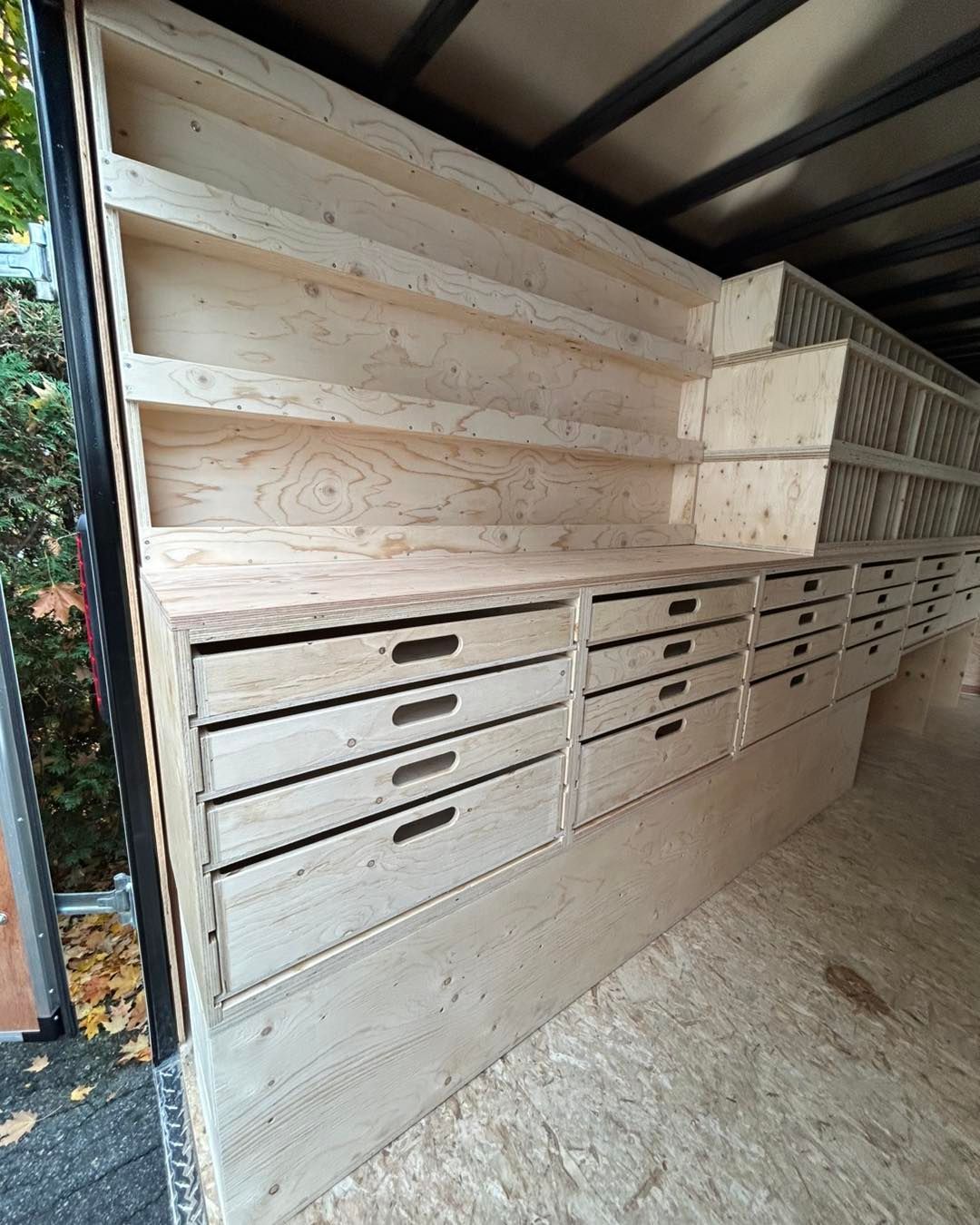 Étagères et tiroirs de rangement en bois intégrés à l'intérieur d'une remorque.