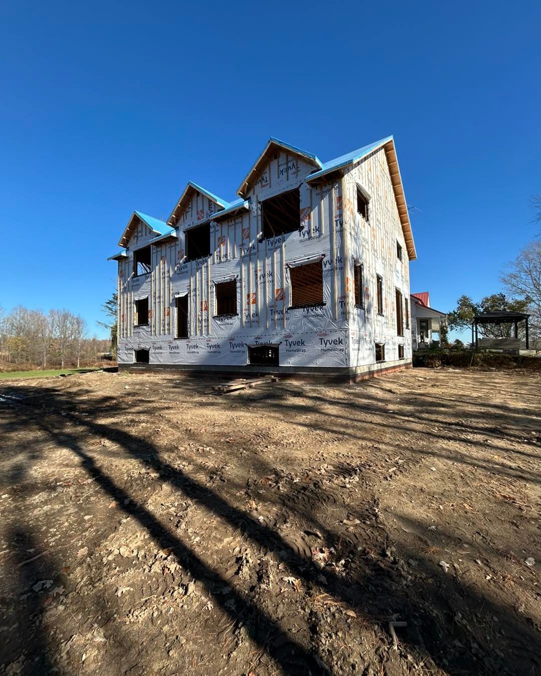 Maison de deux étages en construction. Les murs extérieurs sont recouverts de revêtement. Non finie, les fenêtres et le toit sont visibles.