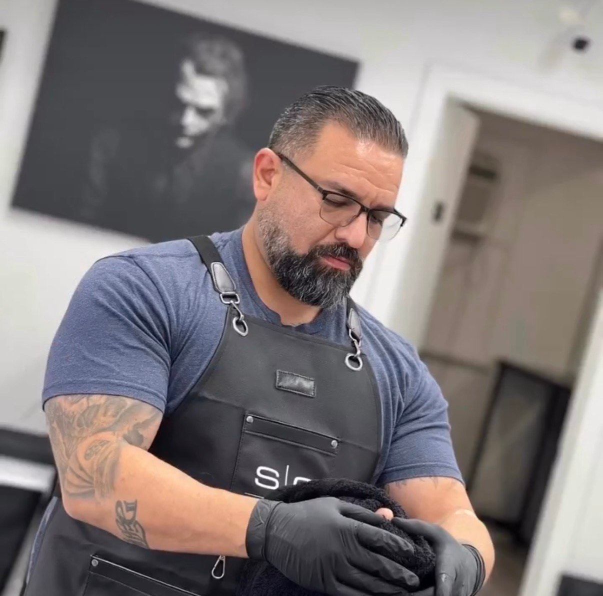 A barber pole with red, white, and black stripes against a brick wall and a blue sky.