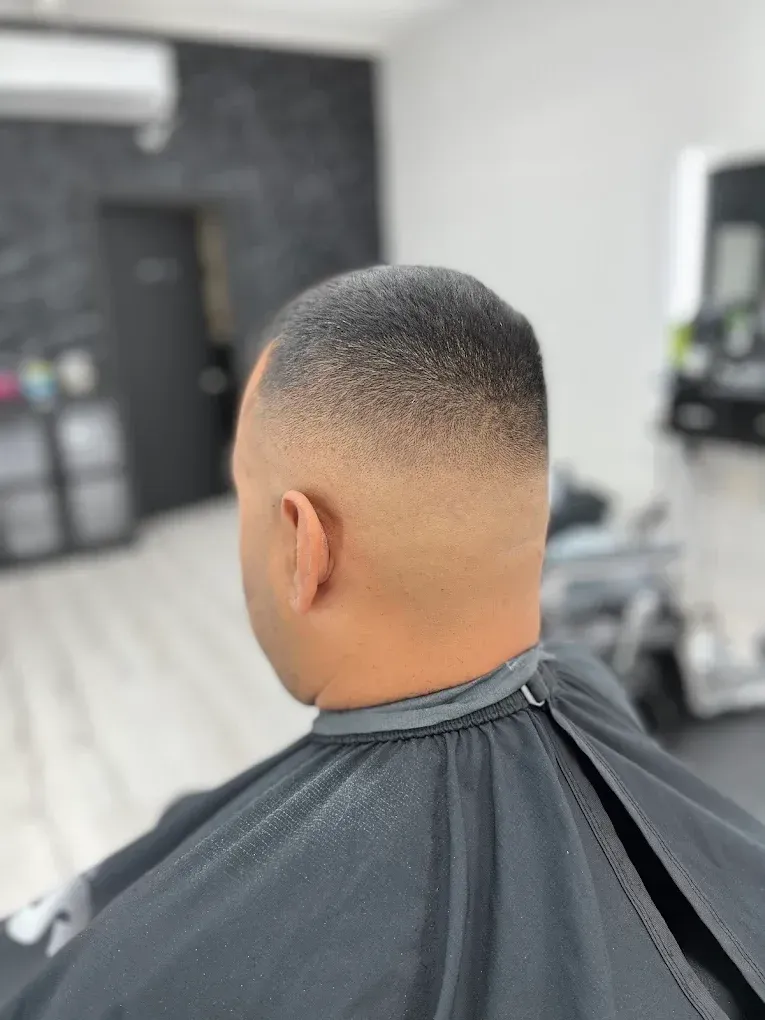 Shaving brush with a silver handle on a table in a barber shop, blurred background with a chair.