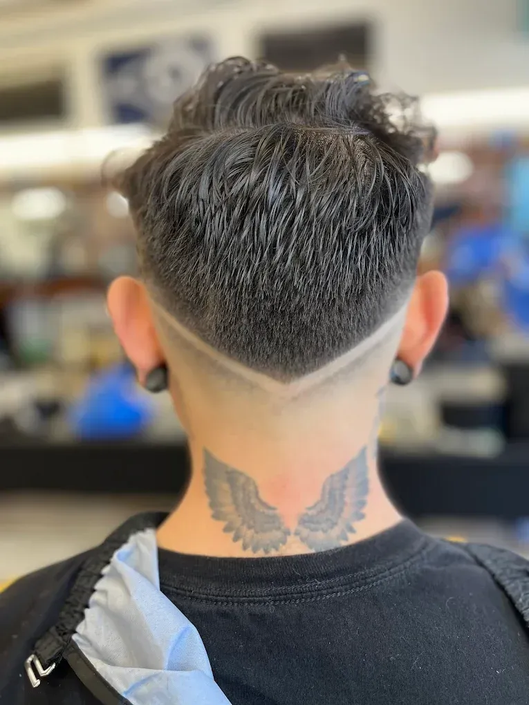 Barber shaves a client's beard with a straight razor in a barber shop, close-up shot.