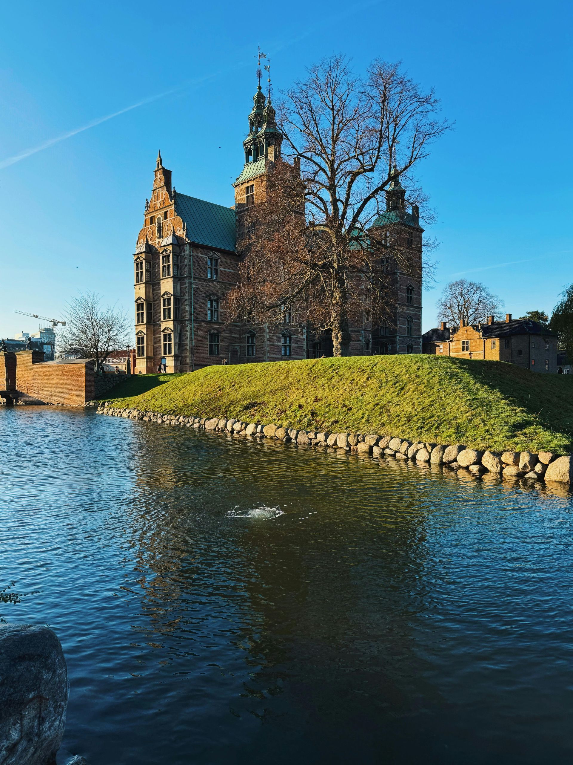 A large castle is sitting on top of a small island in the middle of a body of water.