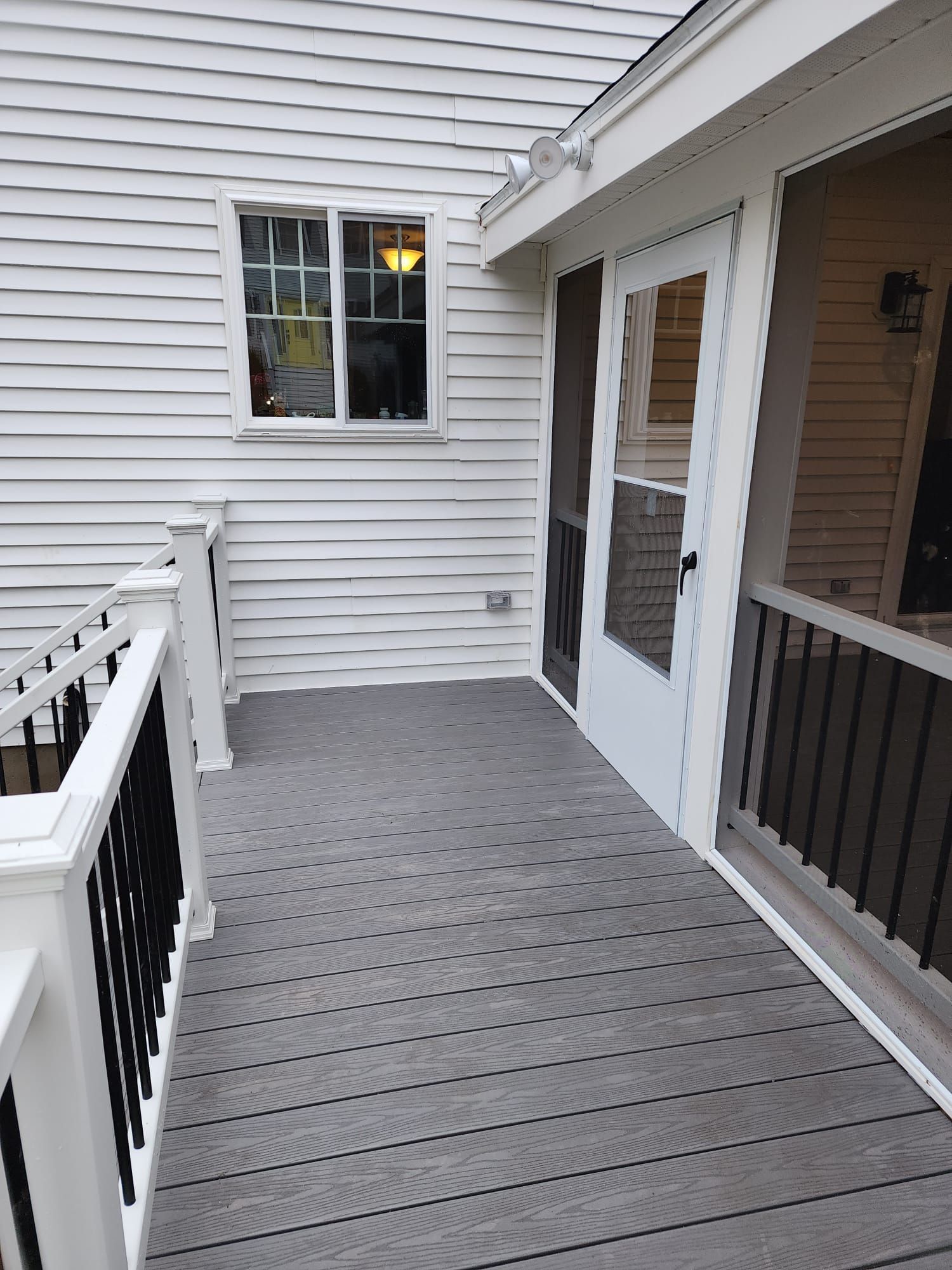 A white house with a screened in porch and stairs leading to it - Plaistow, NH - Dynamic Deck Solutions