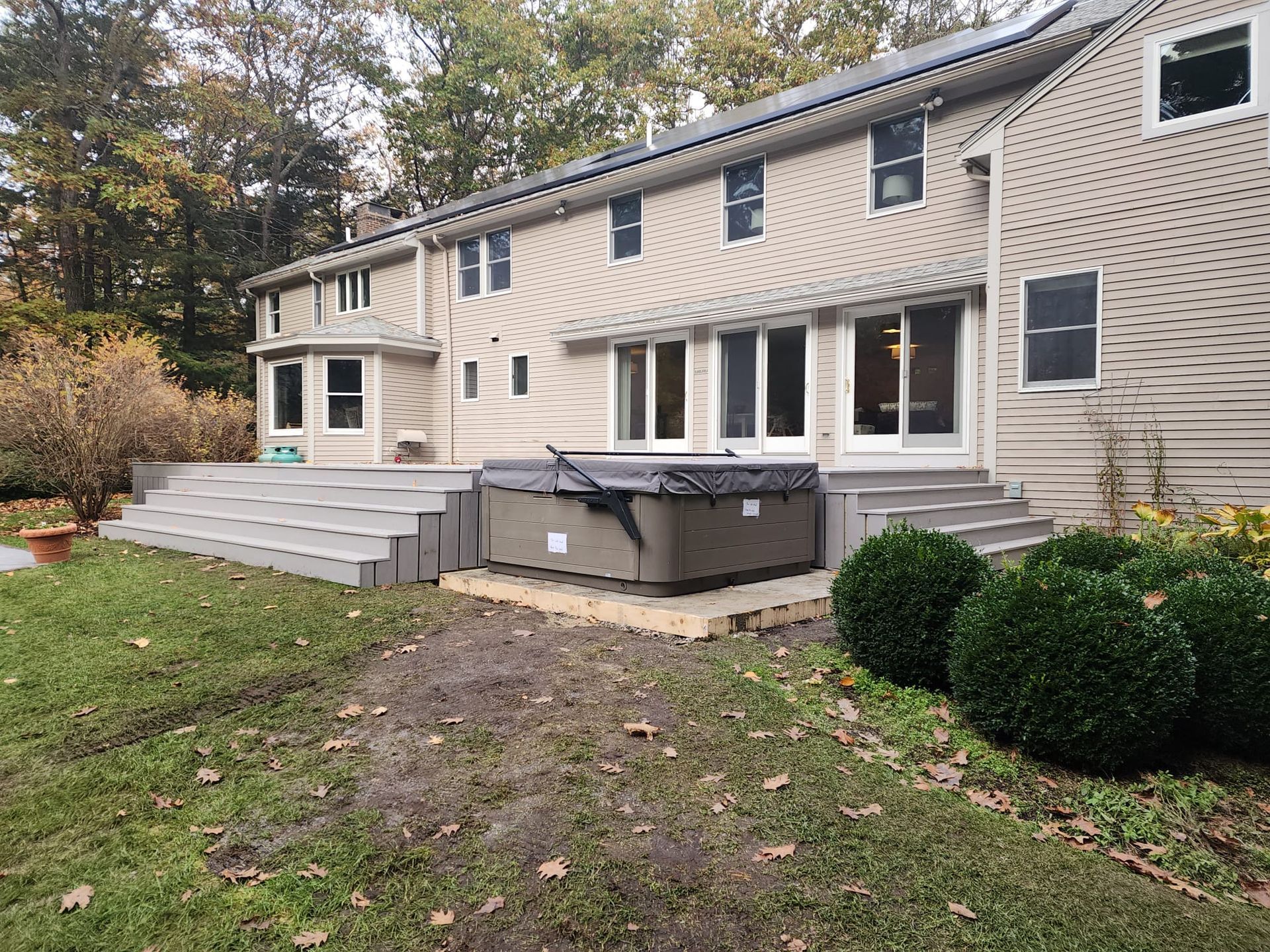 A large house with a hot tub in the backyard - Plaistow, NH - Dynamic Deck Solutions
