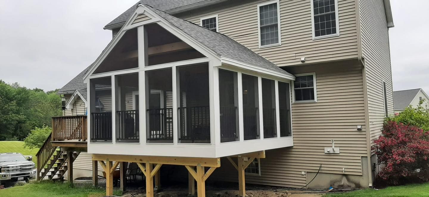 A screened in porch is attached to the back of a house - Plaistow, NH - Dynamic Deck Solutions
