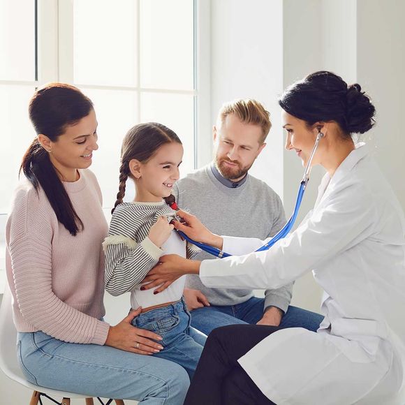 A doctor is listening to a child 's heart with a stethoscope.