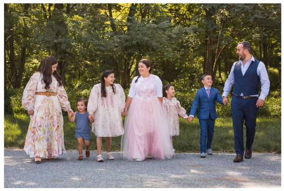 A family is walking down a road holding hands.