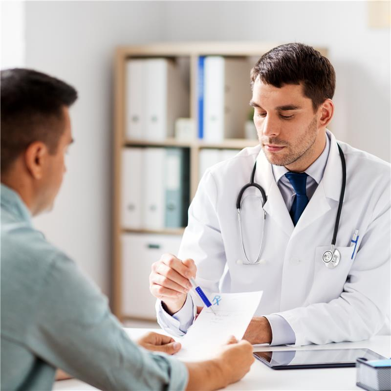 Doctor in white coat reviewing papers with a patient in an office setting