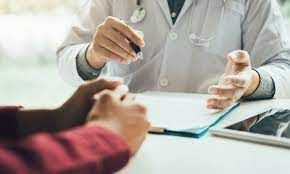 A doctor is sitting at a table talking to a patient.