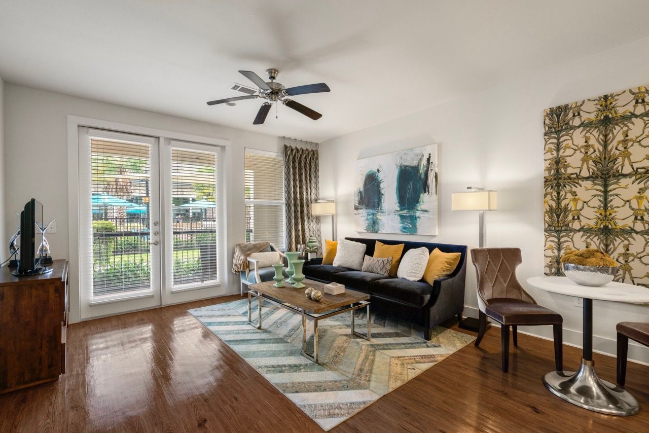 Bright living room in an apartment with a sofa, chairs, coffee table, and French doors to a patio.