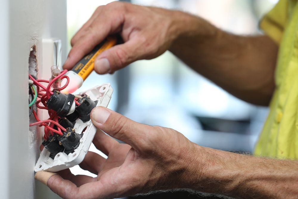 A man is working on a light switch with a screwdriver.