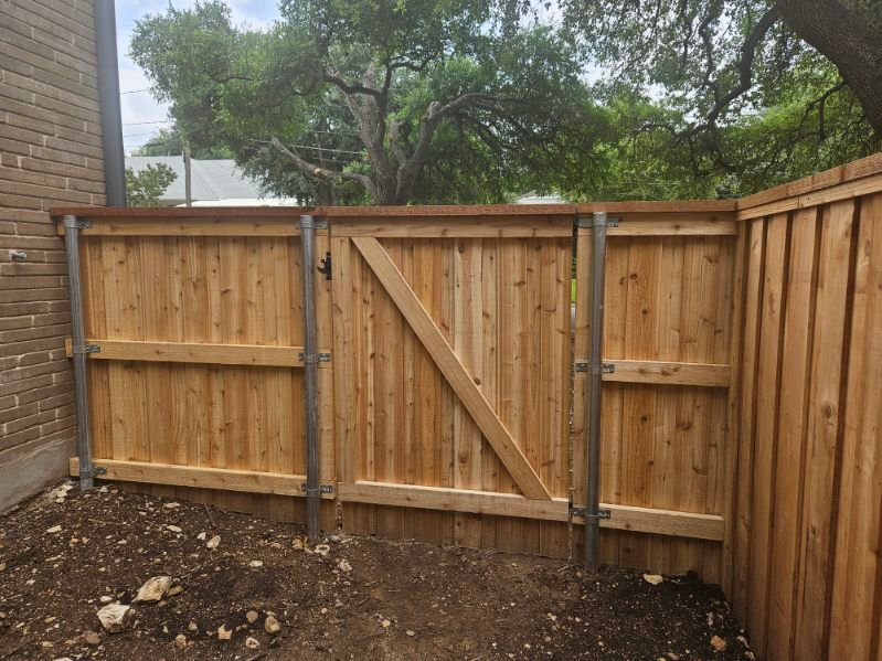 A wooden fence with a gate in the backyard of a house.