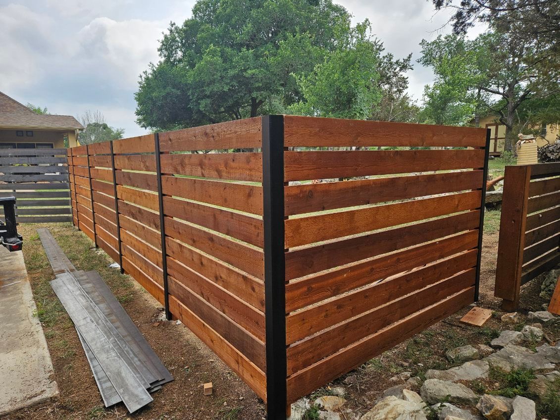 A wooden fence is being built in the backyard of a house.