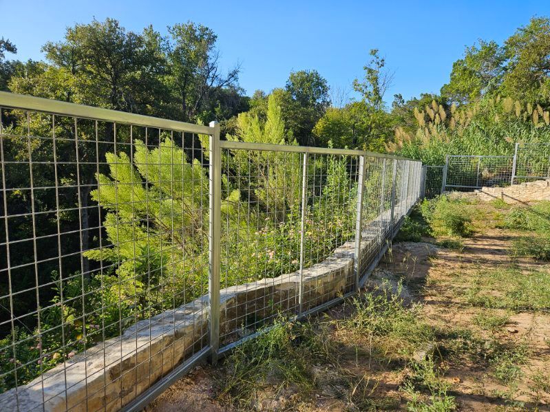 A fence surrounds a lush green field with trees in the background.