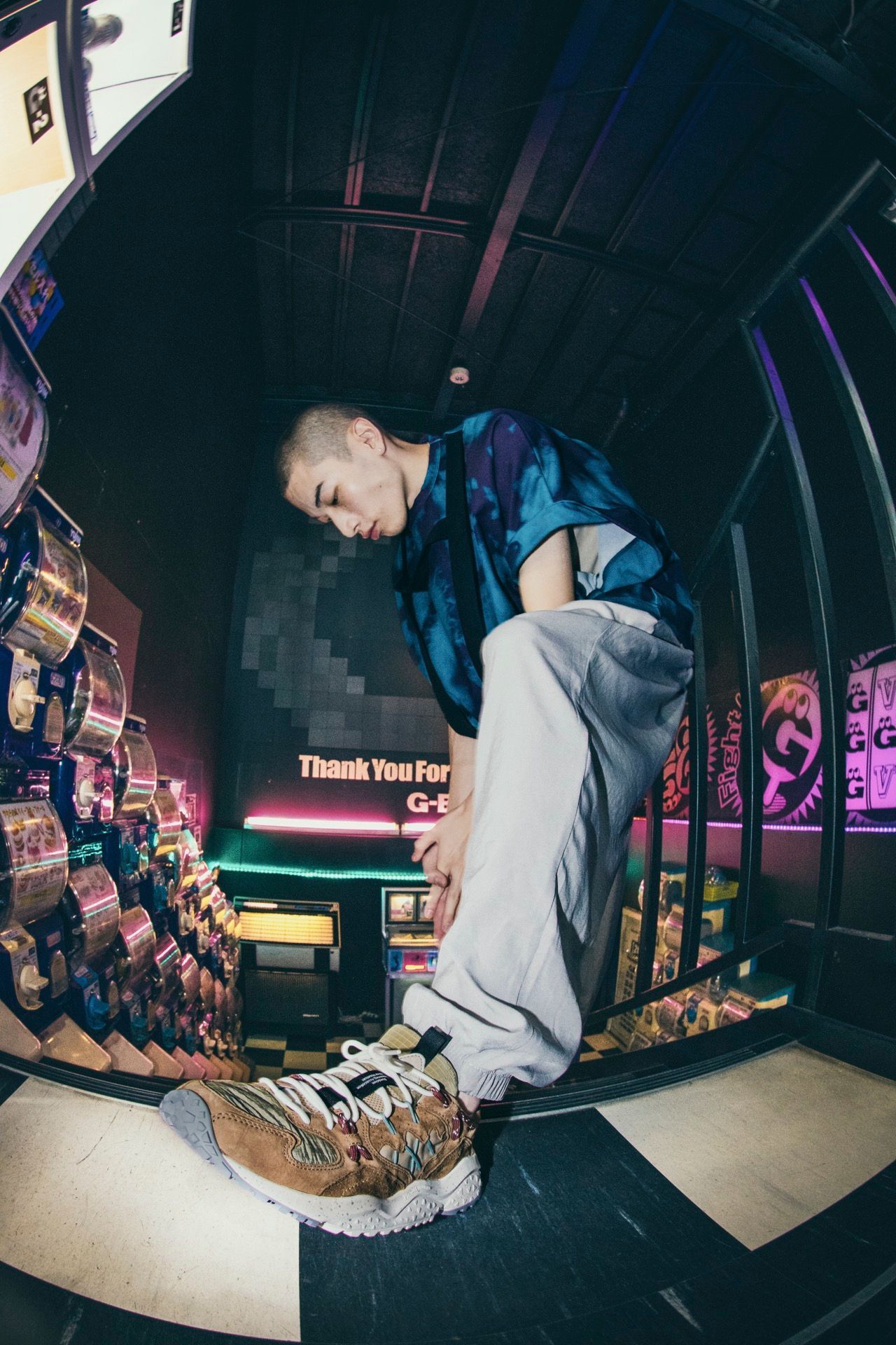 Un uomo guarda dall'alto una donna che si allaccia le scarpe in veranda. Porta buia, colori caldi.