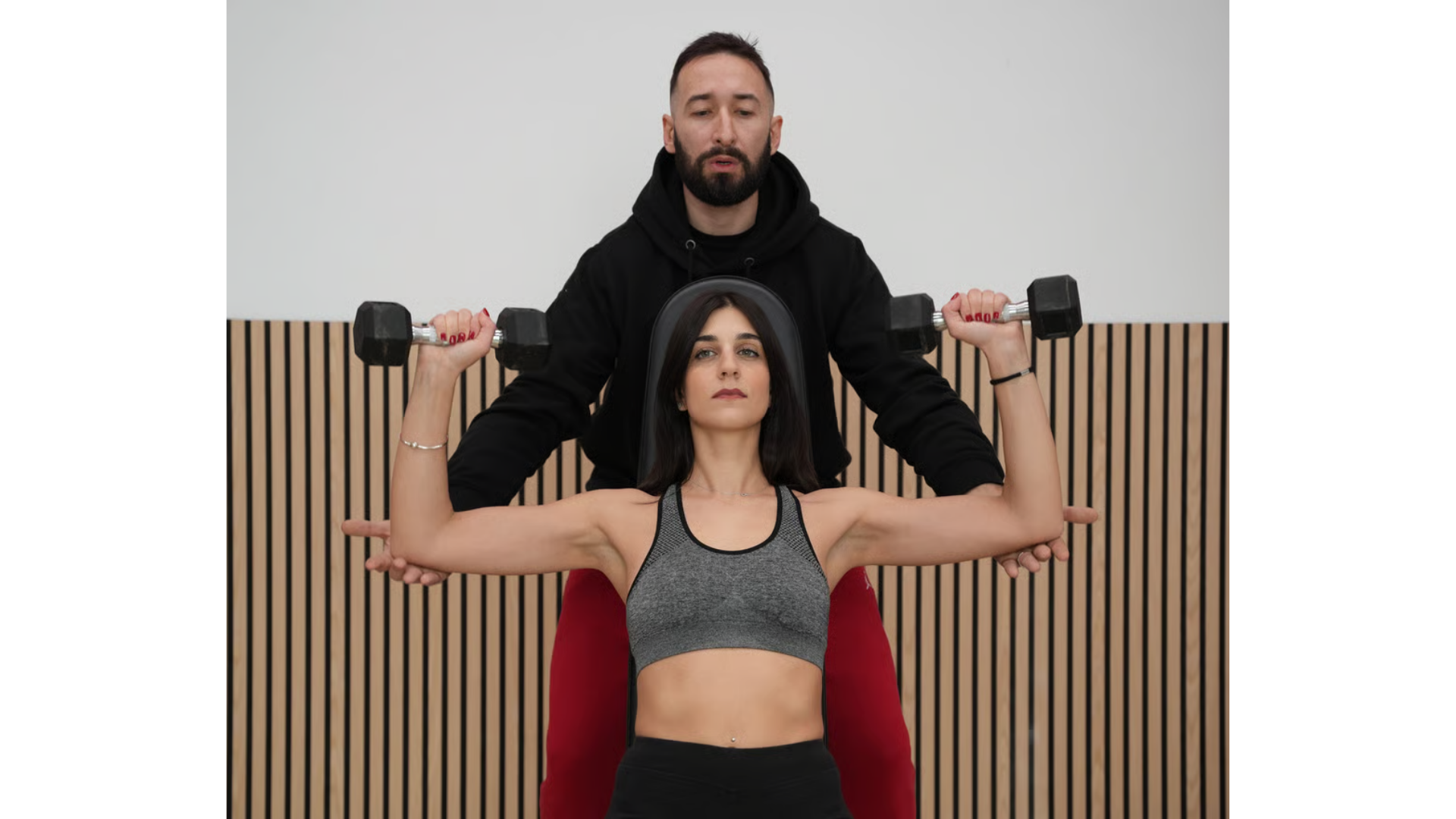 Un istruttore guida una persona mentre esegue una distensione sopra la testa da seduto,