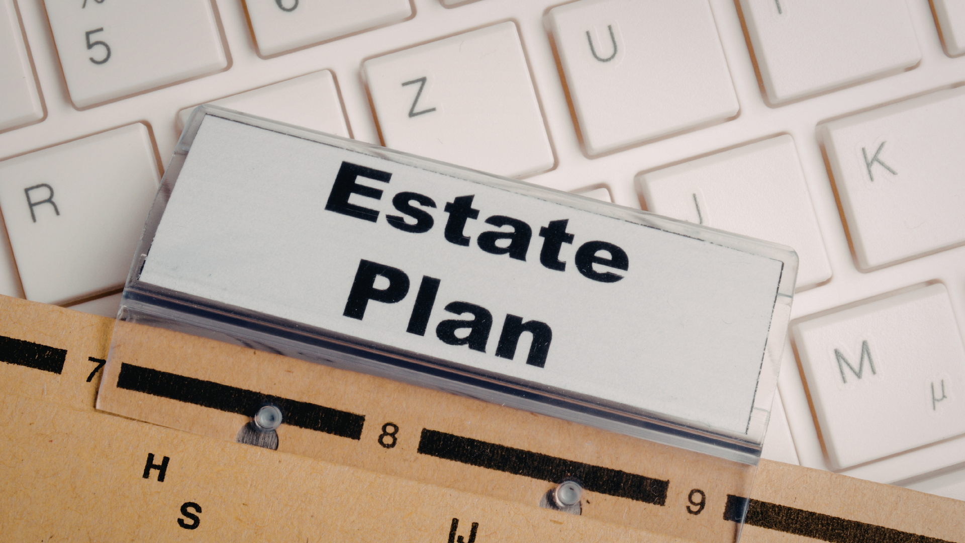 Estate Plan booklet on a keyboard, with a ruler and folder tab in the foreground.