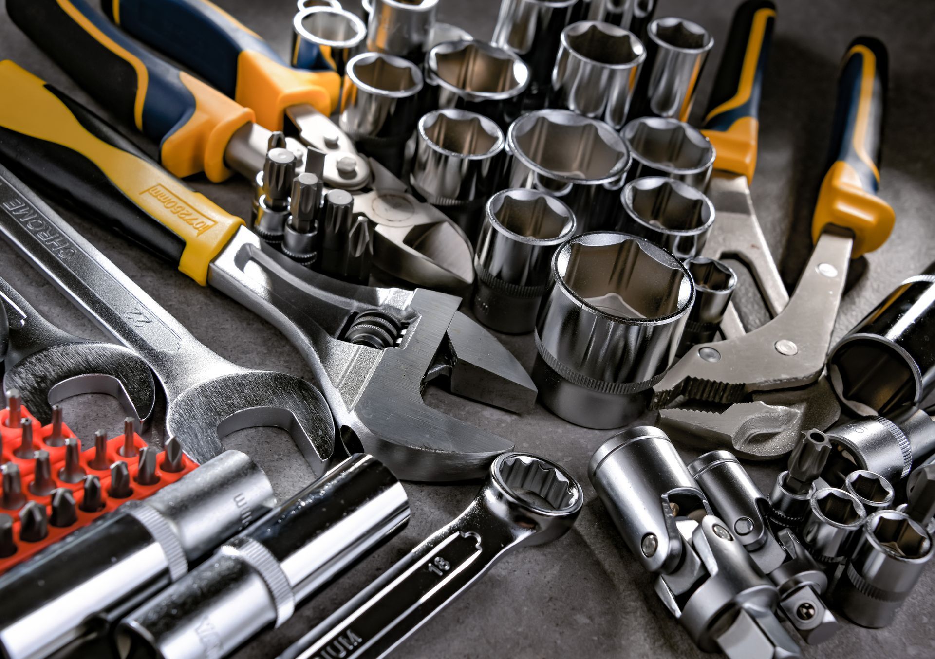 Attrezzi: chiavi inglesi, bussole, pinze e altri utensili sparsi su una superficie.